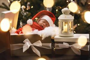 lindo bebé recién nacido con sombrero de santa claus está durmiendo en la caja de regalo de navidad foto