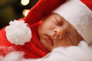 Cute newborn baby wearing Santa Claus hat is sleeping photo