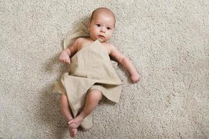 Cute little baby covered with piece of linen fabric photo