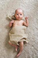 Cute little baby covered with piece of linen fabric photo