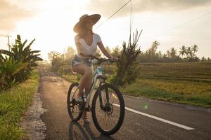 Woman is riding bicycle by narrow country road photo