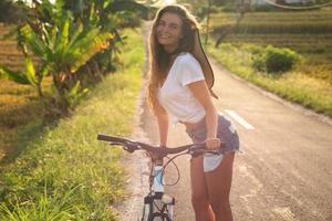 mujer con una bicicleta en un camino rural estrecho foto