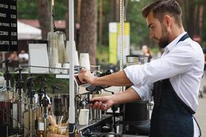 guapo barista durante el trabajo en su cafetería de la calle foto