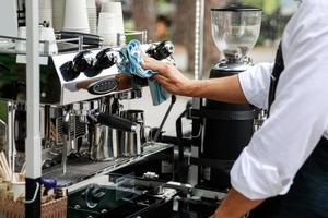 hombre limpiando la máquina de café espresso después de la jornada laboral foto