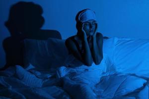 mujer en el dormitorio con un vaso de agua y pastillas para dormir foto