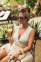 mujer feliz con un cóctel de naranja sentado en la mesa foto