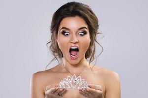 Portrait of young beautiful bride holding diadem photo