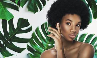 Young and beautiful African woman with perfect smooth skin in tropical leaves photo