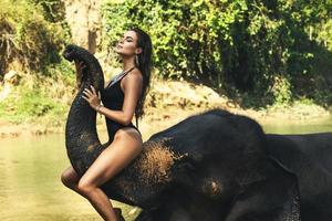 Happy woman is bathing with the elephant in the river photo