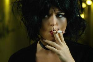 Freaky woman with black hair smoking a cigarette photo