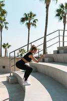 Athletic woman is running on concrete stairs during her street summer workout photo