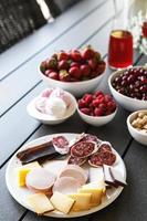 Table full of snacks. Cheese, sausage, salami, meat and berries.. photo