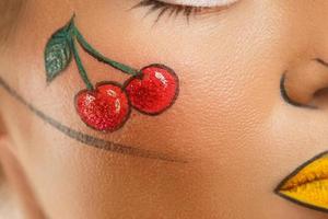 Female face with a drawing of cherry berries photo