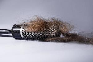 Metal round hairbrush and clump of hair photo