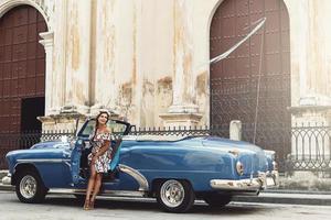 Woman wearing beautiful dress and retro convertible car photo