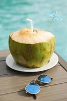 Fresh coconut drink and sunglasses on the table photo