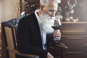 Handsome bearded senior man drinking red wine photo