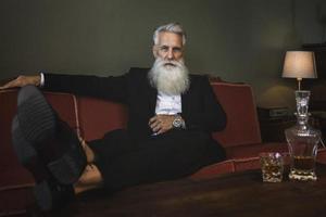 Handsome and bearded senior man drinking whiskey photo