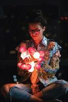 Happy woman wearing glowing jacket with sequins is holding light balls in her hands photo