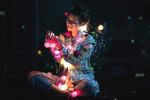 Happy woman wearing glowing jacket with sequins is holding light balls in her hands photo