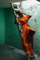 Sensual woman wearing beautiful long dress on the old wooden ladder photo