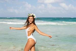 mujer sexy con traje de baño blanco está posando en la playa foto