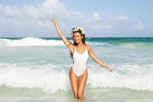 Sexy woman wearing white swimsuit is posing on the beach photo