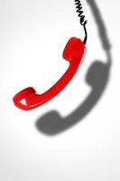 Red telephone handset with a dark shadow. Concepts of hotline, support or phone scams. photo