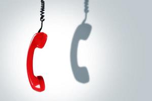 Red telephone handset with a dark shadow. Concepts of hotline, support or phone scams. photo