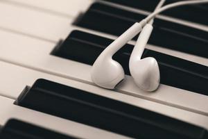 Closeup of earphones over piano or synthesizer keyboard photo