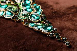 Luxury necklace with green gemstones on the brown velvet photo