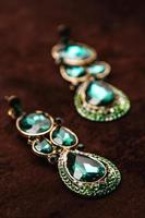 pendientes de lujo con piedras preciosas verdes en el terciopelo marrón foto