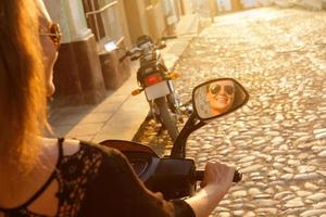 Woman traveler driving scooter by the old city streets photo