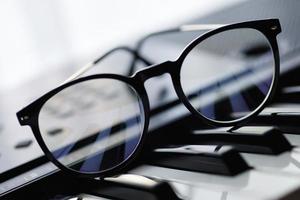 Closeup of eyeglasses on the synthesizer keyboard photo