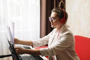 mujer joven músico tocando sintetizador en casa foto