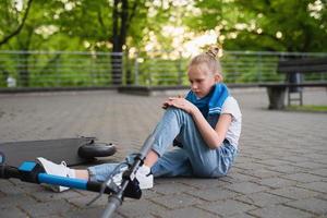 Electric scooter accident - girl suffering of pain after knee injury photo