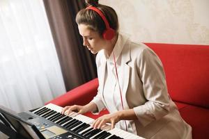 Young woman musician playing synthesizer at home photo