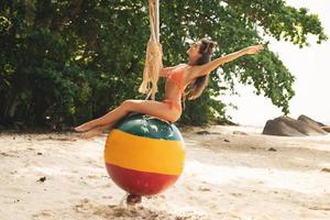 Happy woman sitting on swings made from old buoy photo