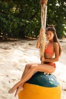 Happy woman sitting on swings made from old buoy photo