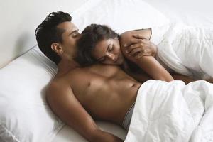 una pareja joven y hermosa está acostada en la cama por la mañana foto