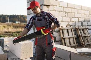 Bricklayer man is sawing autoclaved concrete blocks photo
