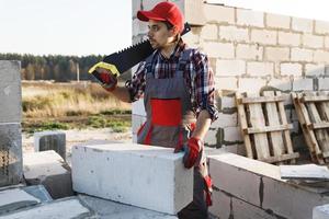 Bricklayer man is sawing autoclaved concrete blocks photo