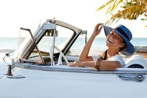 mujer joven feliz y coche descapotable retro foto