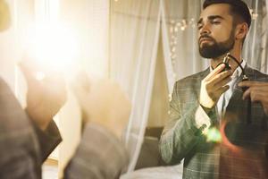 Handsome bearded man is using atomizer nozzle with perfume photo