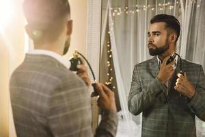 Handsome bearded man is using atomizer nozzle with perfume photo