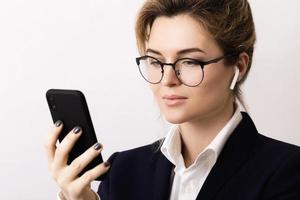 Young businesswoman talking by phone using wireless earbuds photo