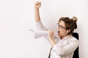 mujer de negocios motivada gritando en la hoja de papel enrollada como un altavoz