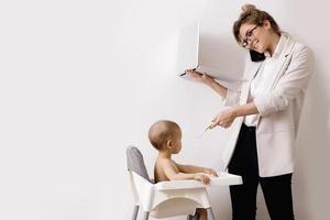 Young and busy businesswoman is working and holding her little baby photo