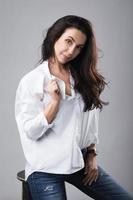 Beautiful middle aged fashion model wearing white shirt and jeans in a photo studio