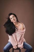 Beautiful middle aged woman wearing warm woolen sweater over brown background photo